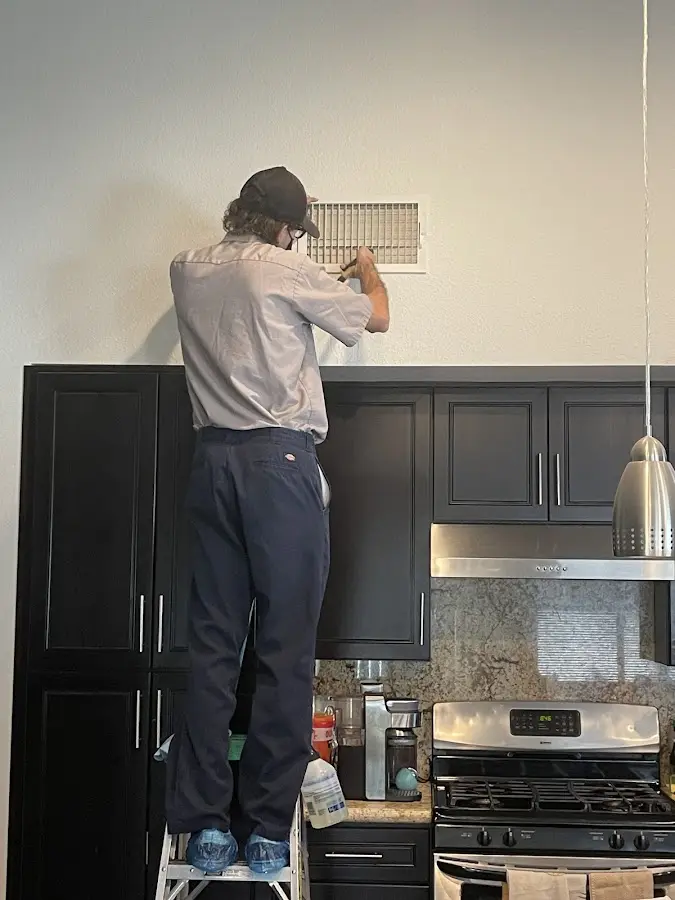 Technician inspecting an air vent during HVAC service in Lovington
